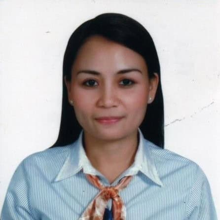 A woman with straight dark hair, wearing a striped shirt, white collar, and an orange scarf, poses against a plain white background.